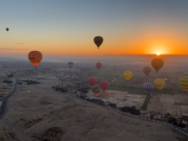 Hot air balloons soaring in the sky at sunrise, showcasing the beauty of Egypt's landscapes for holiday packages and tours.